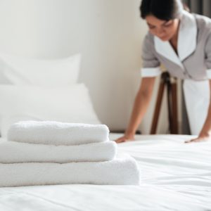 Ein junges Hotelzimmermädchen macht das Bett mit sauberen, frischen Handtüchern